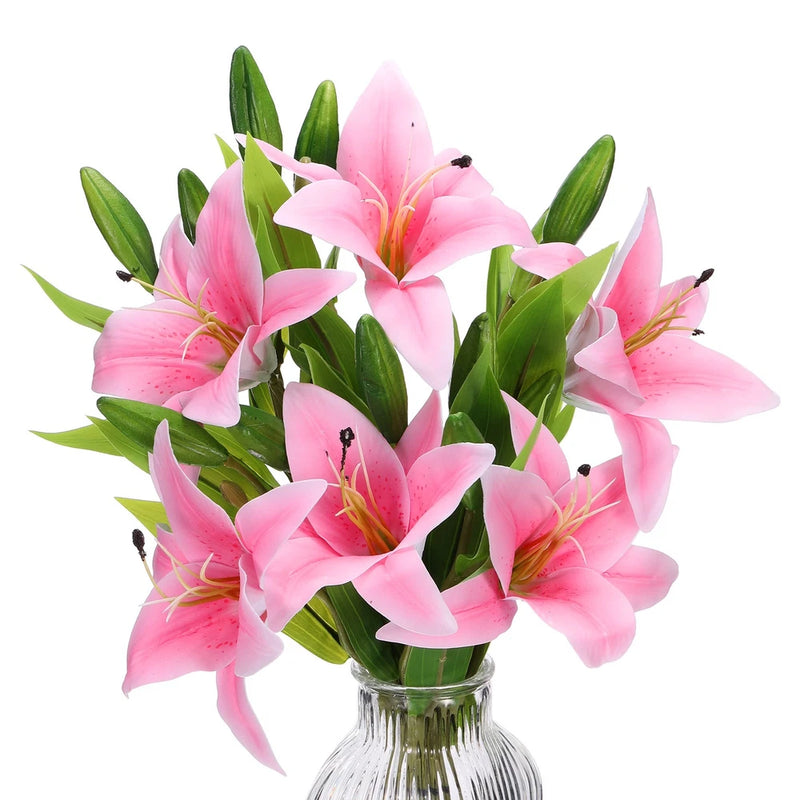Pink artificial lily flower bouquet with green leaves in clear glass vase