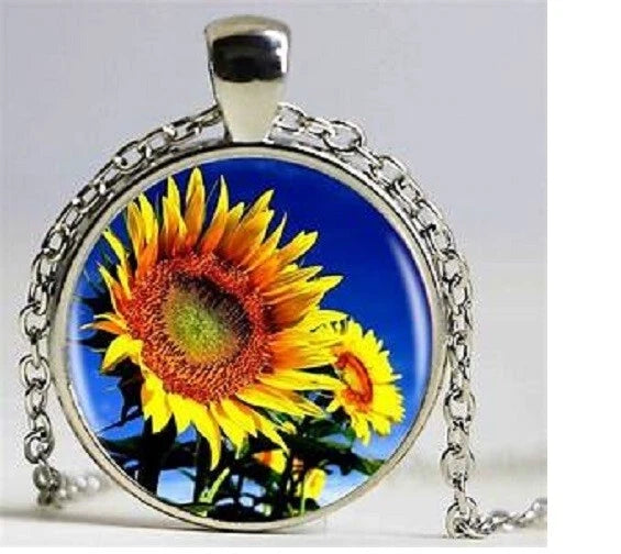 Sterling silver necklace with round sunflower charm pendant, blue background art