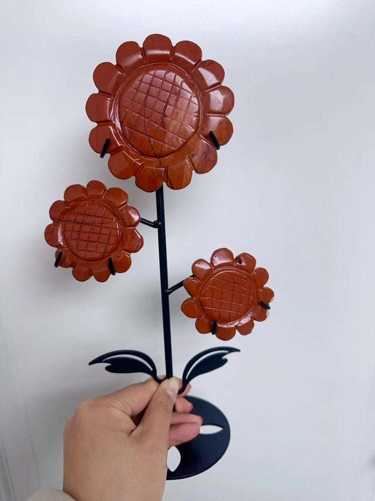 Red jasper sunflower decoration on black metal stand, three carved flower heads with leaves