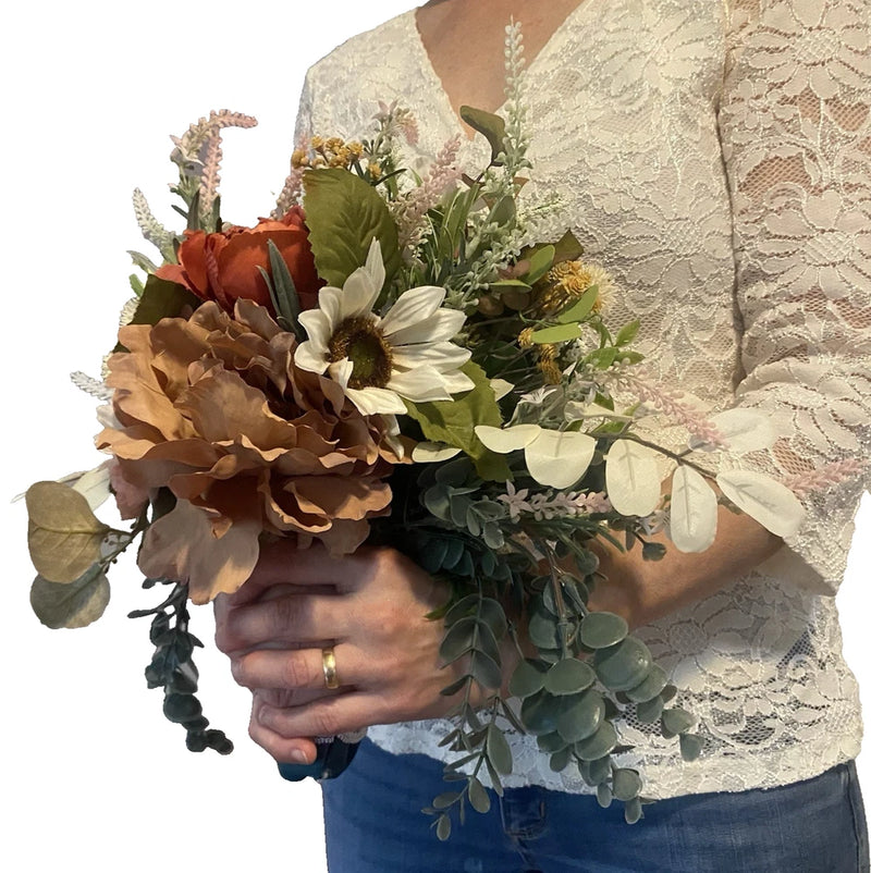 Handmade faux bridal bouquet with rust, brown, and white flowers and green foliage