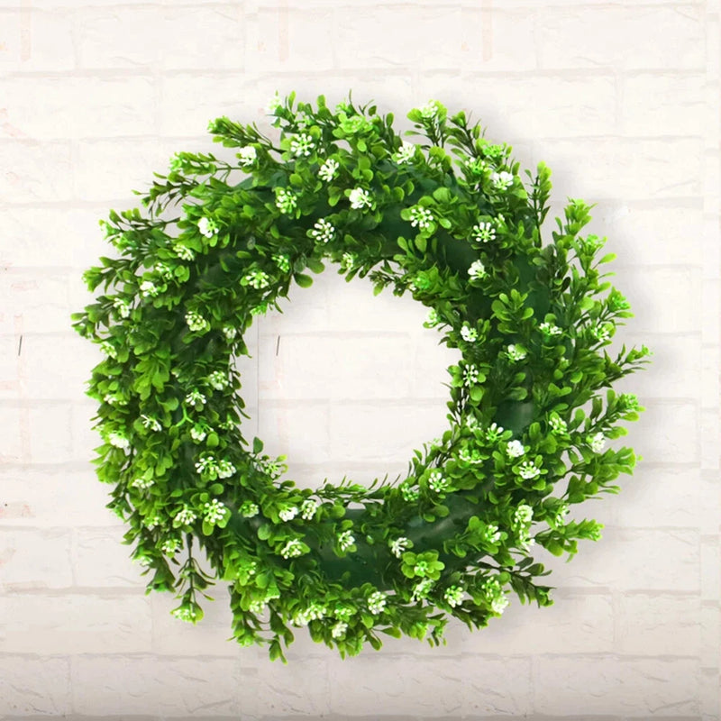 Artificial green plant wreath with dense leaf clusters and small flower-like accents
