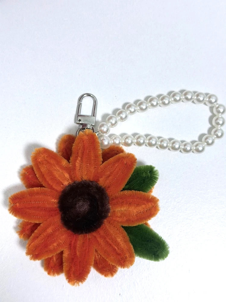 Orange fuzzy sunflower keychain with black center, green leaf, pearl bead loop, metal clasp