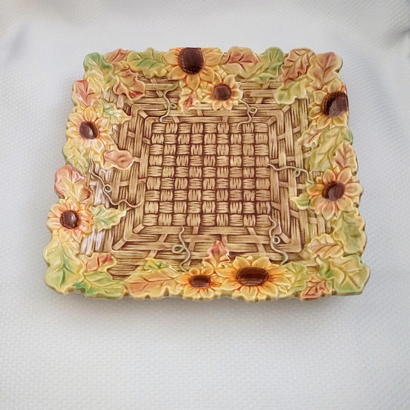Square ceramic serving plate with raised sunflower and basket motif, decorative floral border