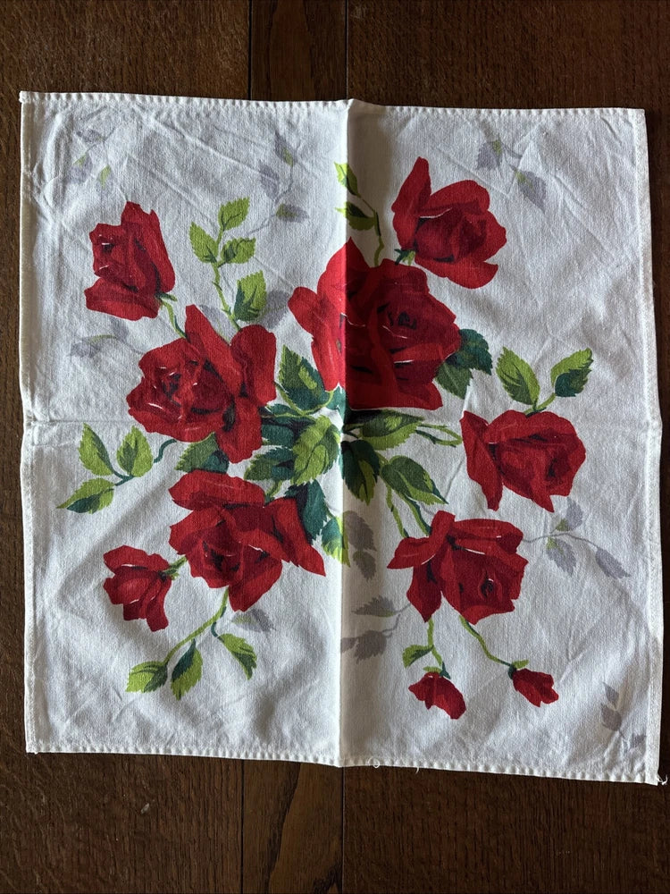Vintage tea napkin with red roses and green leaves on white