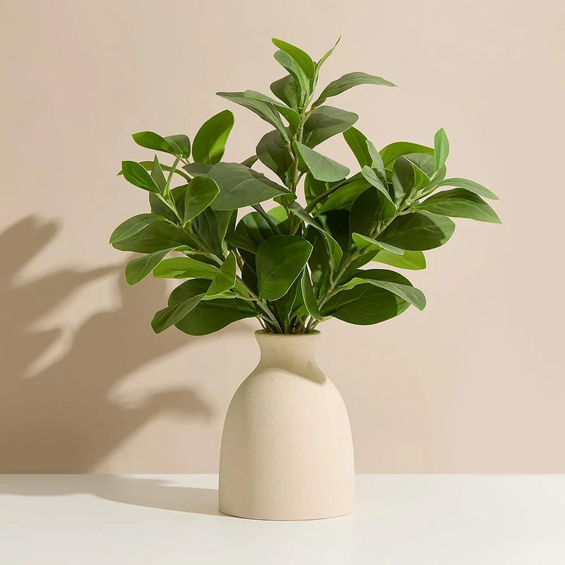 Artificial eucalyptus plant with green leaves in a white potted vase
