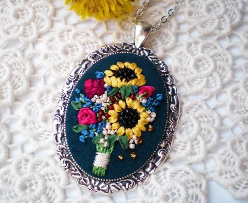 Embroidered sunflower pendant necklace, oval silver frame with multicolor thread floral.