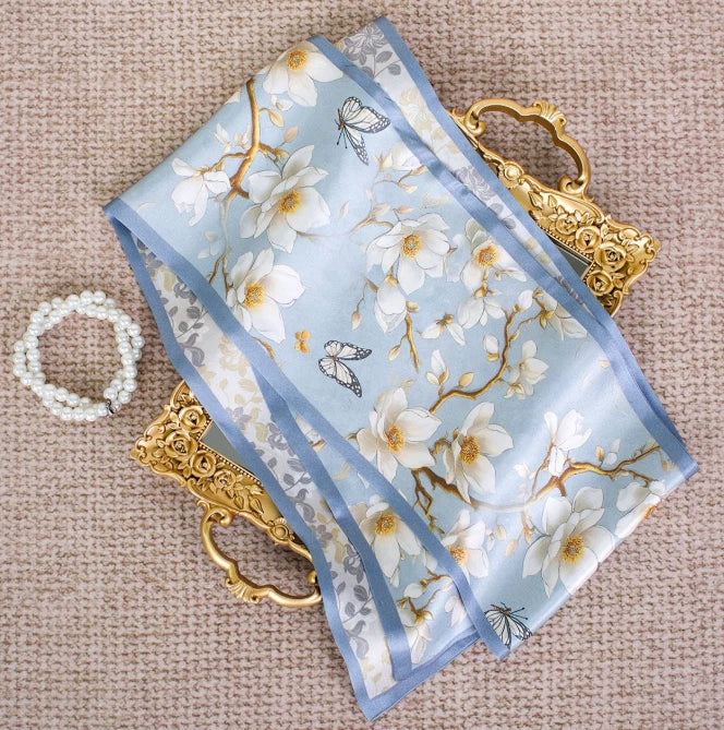 Silk neckerchief scarf with light blue floral print and striped border, folded fabric
