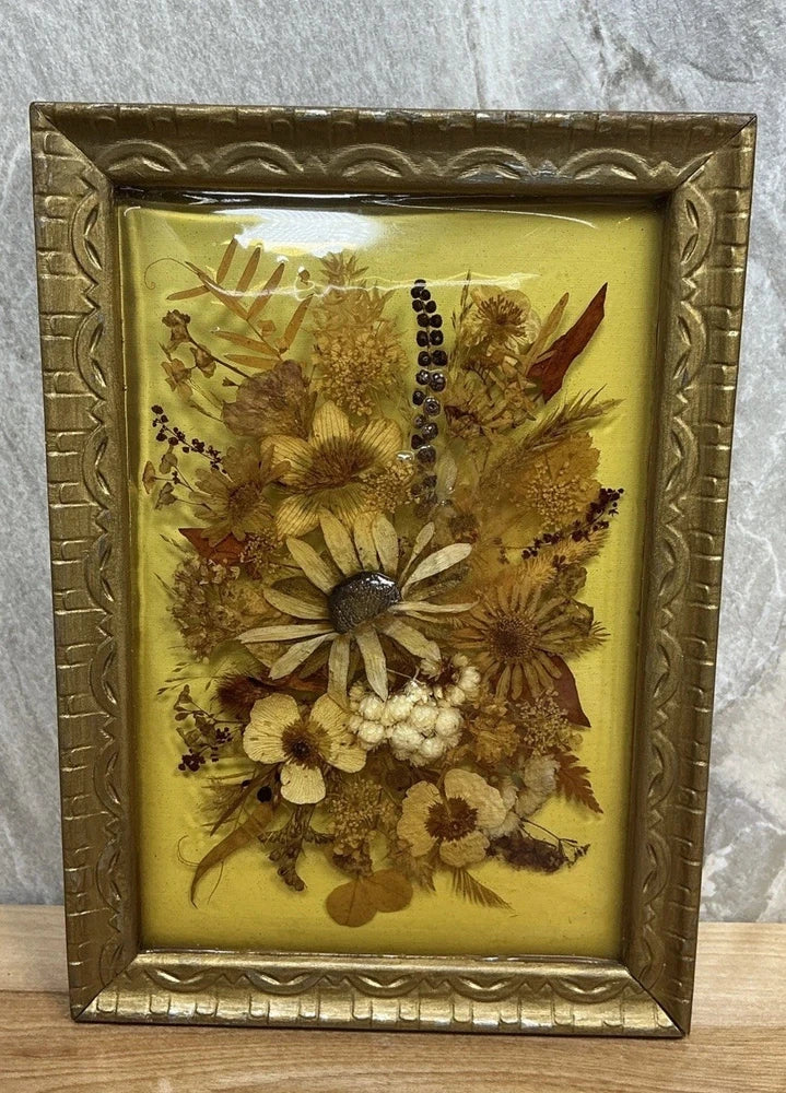 Ornate gold framed dried wildflower art with clear resin over pressed blossoms on yellow