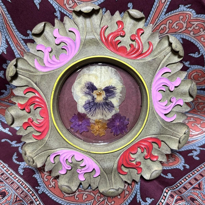 Pressed flower artwork with dried flower in circular center, ornate hand-painted frame