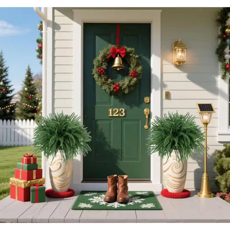 Artificial green pine branches in decorative pots with Christmas gift and doormat decor