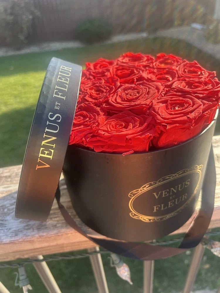 Small round black Venus Et Fleur box with red preserved roses, gold logo ribbon
