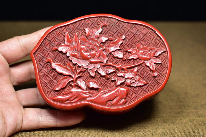 Red vintage lacquer jewelry box lid with embossed peony flowers and geometric border