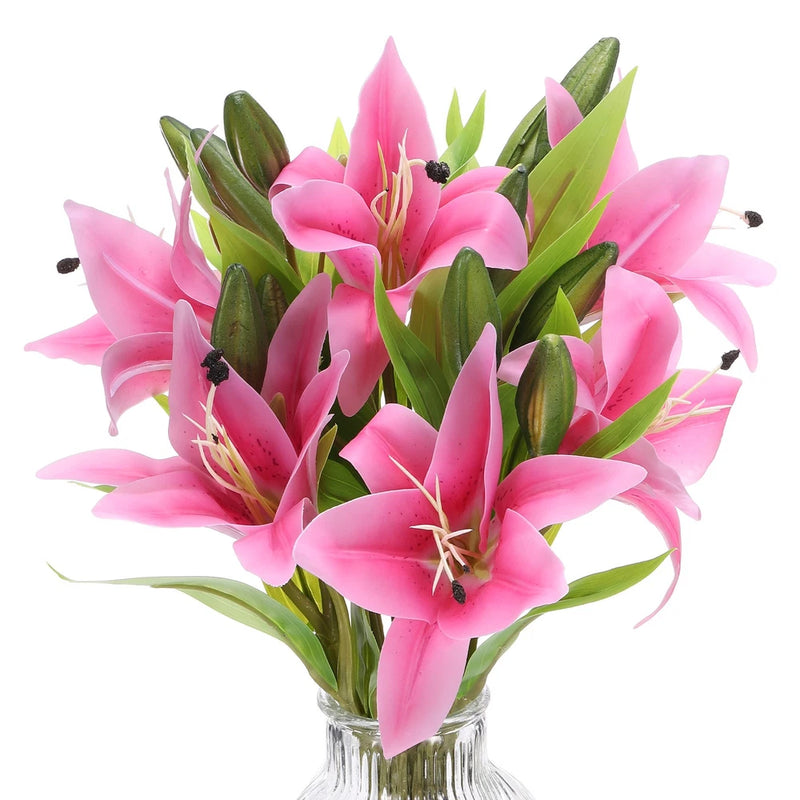Artificial light pink lily flowers with green leaves in a clear vase