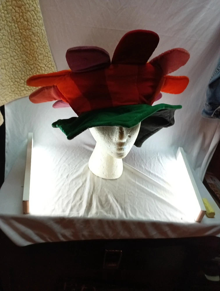 Multicolor novelty sunflower-shaped hat with layered petals and dark brim on mannequin