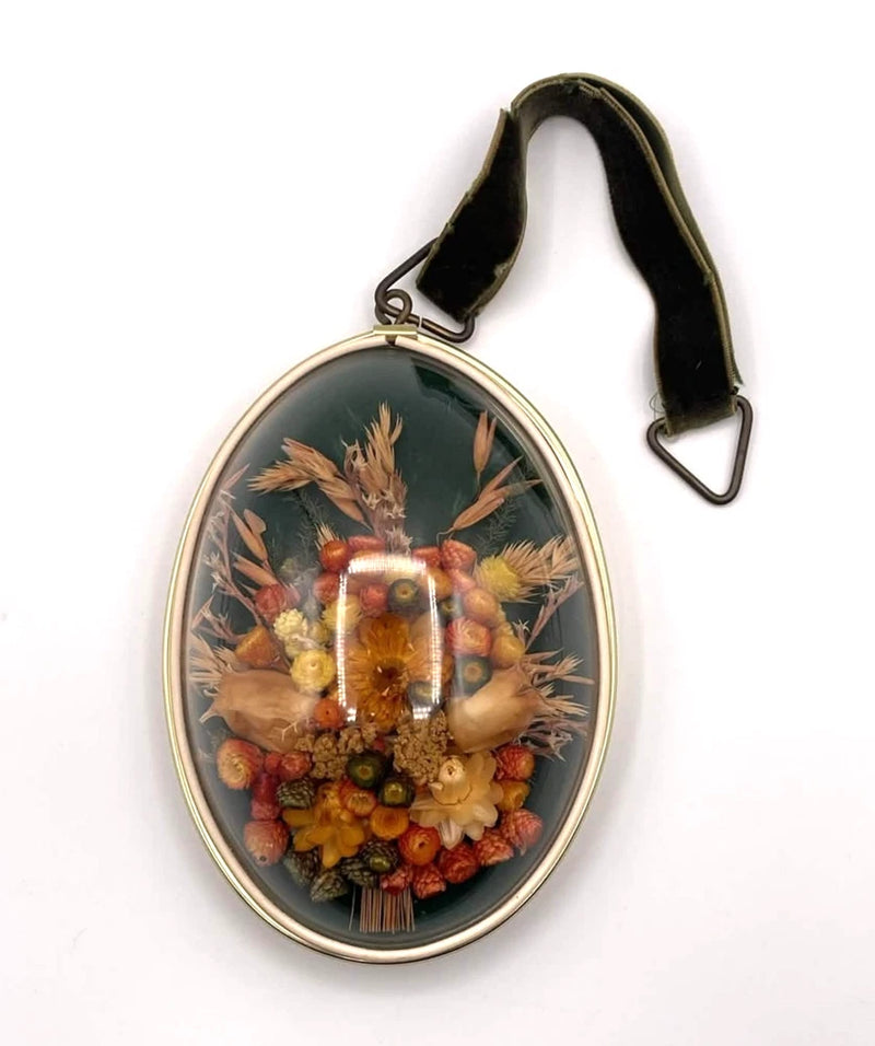 Oval convex shadow box wall hanging with dried flowers under glass dome and hanging strap