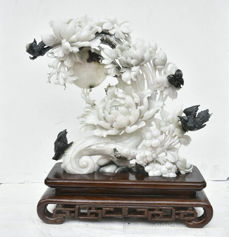 White jade carved peony and bird sculpture with swirling flowers on wooden base