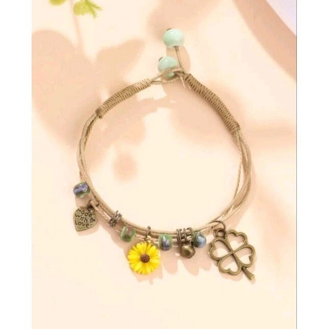 Braided rope charm bracelet with yellow sunflower, heart, clover, and bead accents