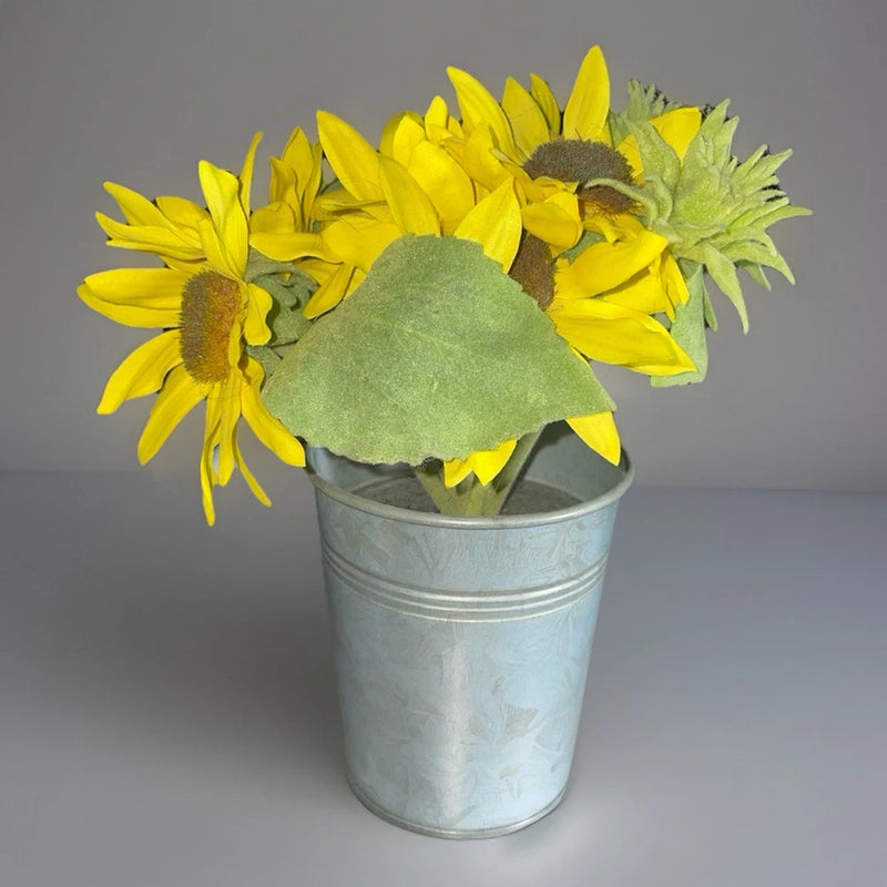 Silver metal planter with artificial yellow sunflowers and green leaves