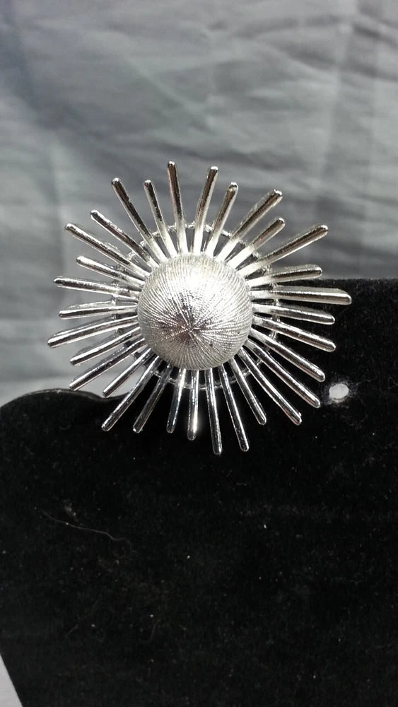 Silver tone sunburst brooch pin with round center and radiating spike rays