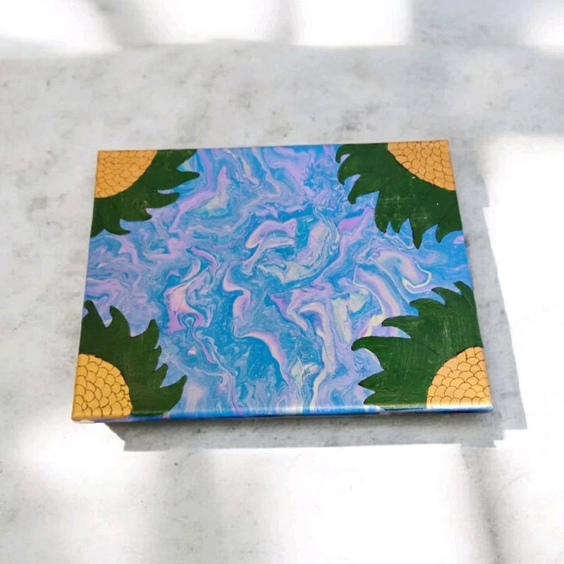 Small unframed sunflower acrylic canvas painting with blue abstract center and green leaves