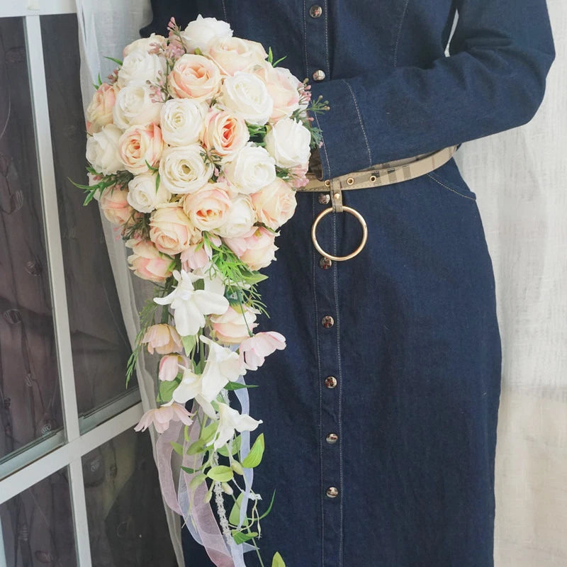 Bride holding waterfall rose bouquet with pink and white blooms and greenery