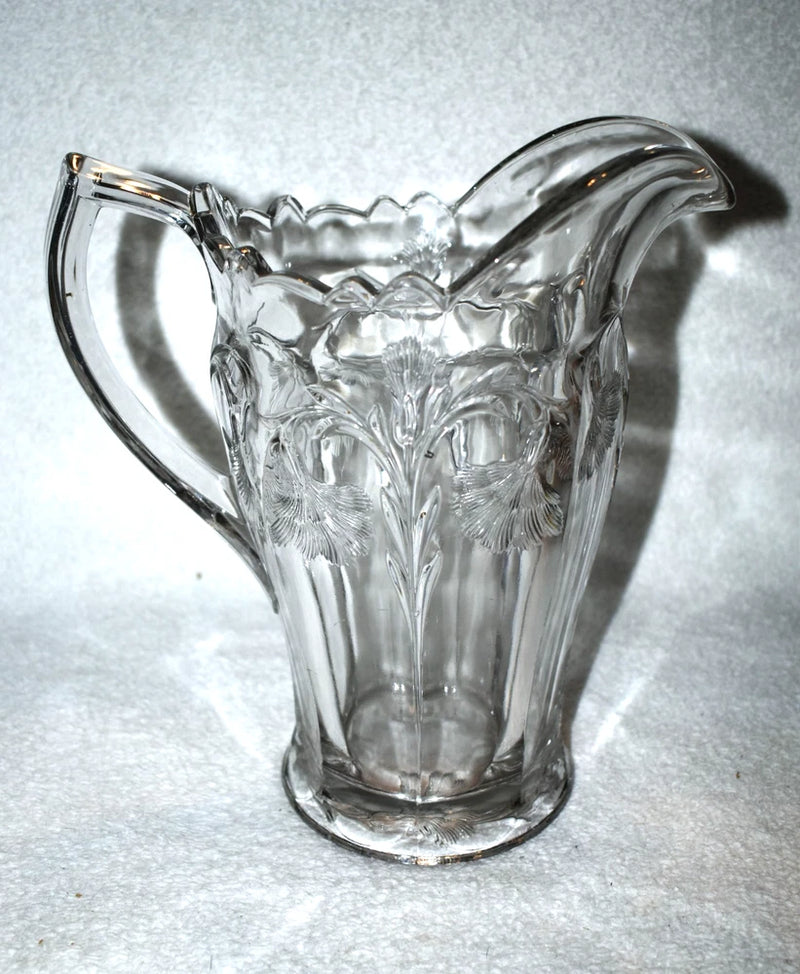 Clear glass carnation pitcher with ornate relief pattern and curved handle