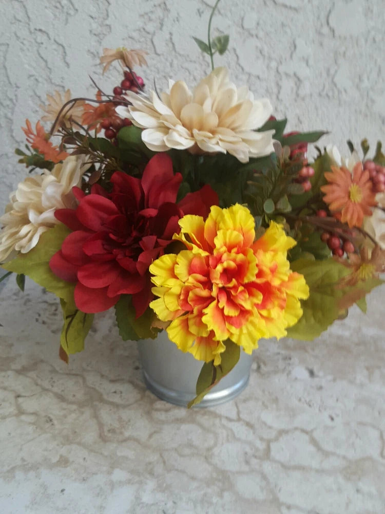 Autumn floral centerpiece in a gray vase with red, yellow sunflower-style blooms and greenery