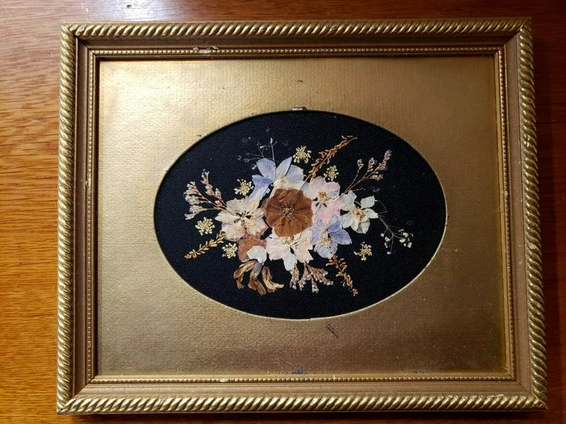 Vintage gold framed pressed flower art with oval dark backdrop and dried bouquet floral design