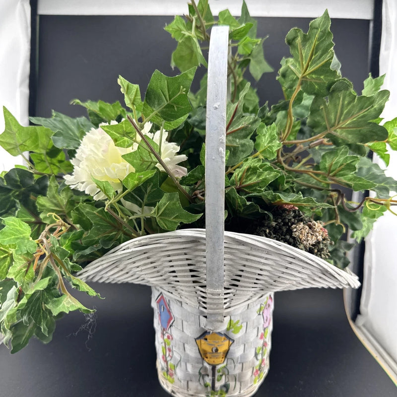 Faux floral arrangement in white wicker basket with green leaves and cream carnations