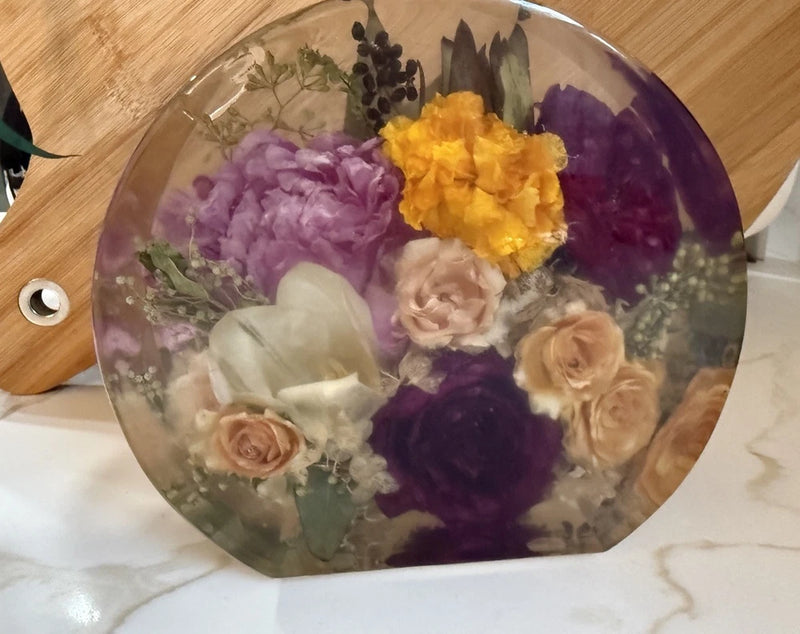 Round poured resin dried-flower block with purple, yellow, and beige blooms inside