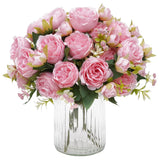 Artificial peony bouquet with light pink blooms in clear glass vase with greenery