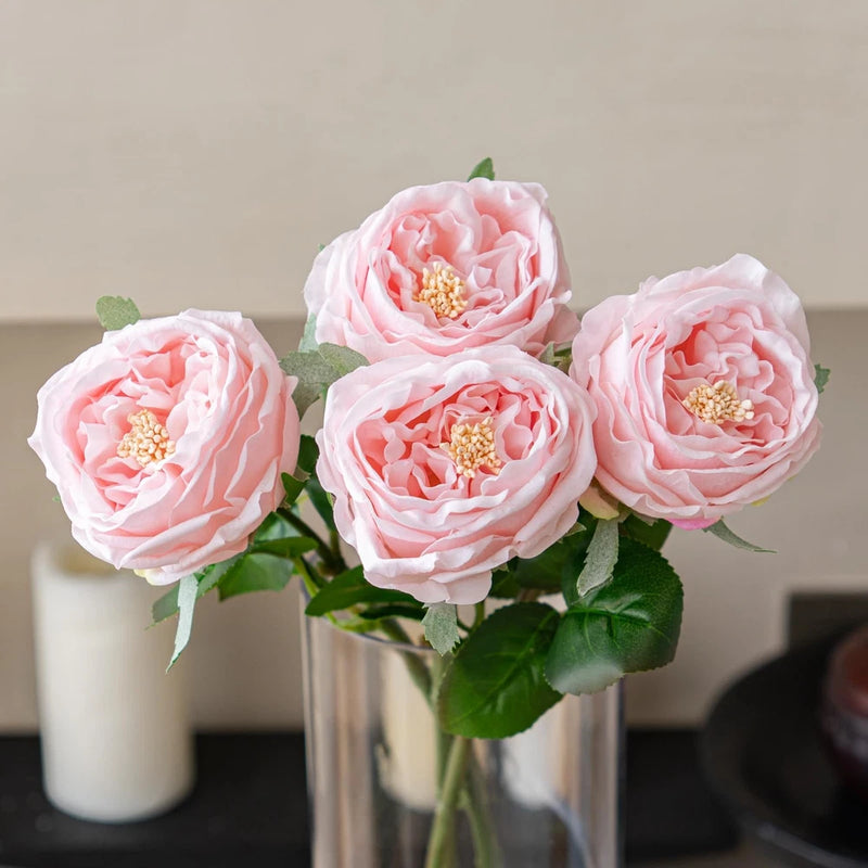 Pink artificial peony-style rose flowers with gold centers and green leaves, 4 stems in vase
