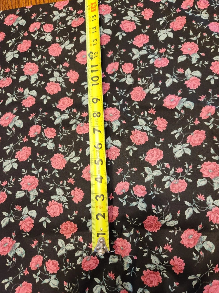 Black cotton floral fabric with pink roses and green leaves; tape measure detail