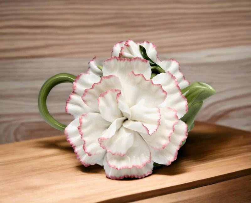 White ceramic flower teapot with pink-edged ruffled carnation and green leaves