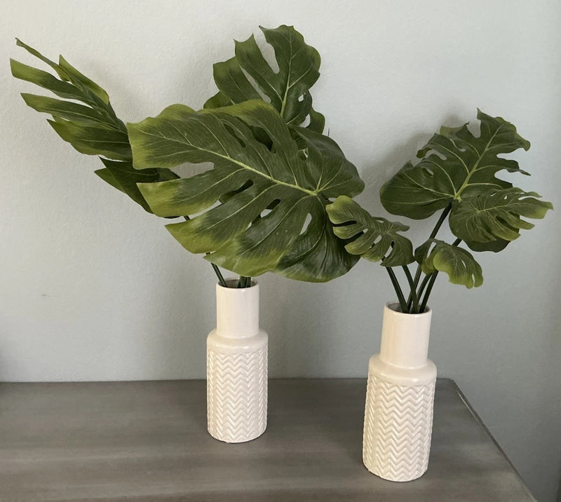 Pair of artificial indoor monster-leaf plants with green leaves in white ceramic pots