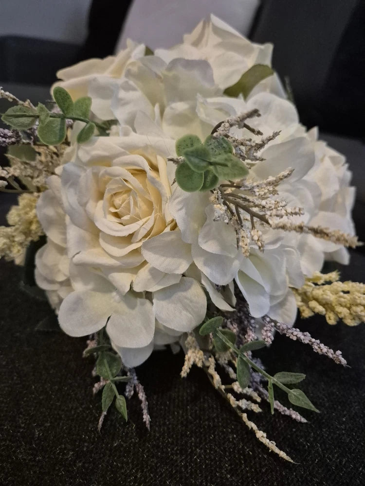 Artificial white and cream rose wedding bouquet with green leaves and dried sprigs