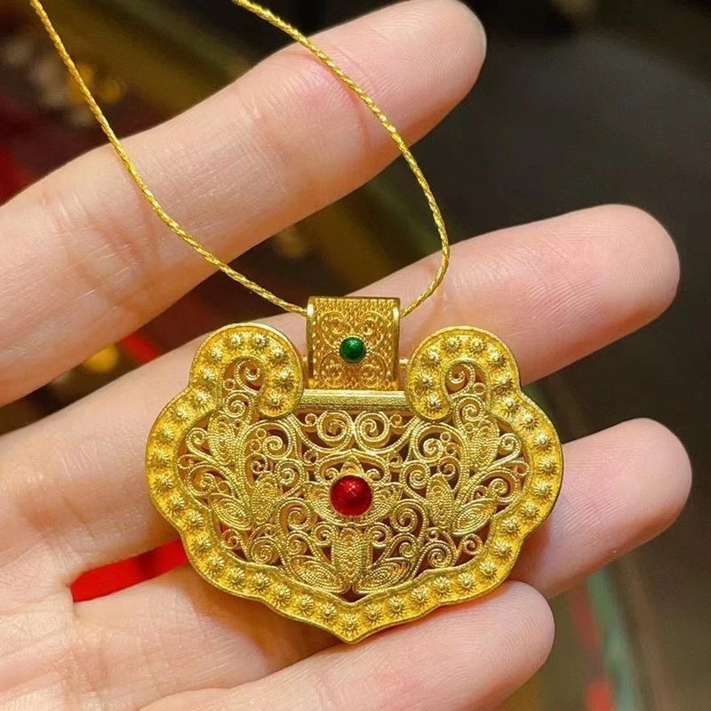 Chinese-style gold filigree pendant with red center gem, on a chain