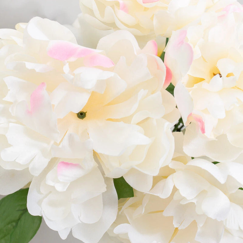 Artificial peony floral bush with large white and pale pink blooms and green leaves