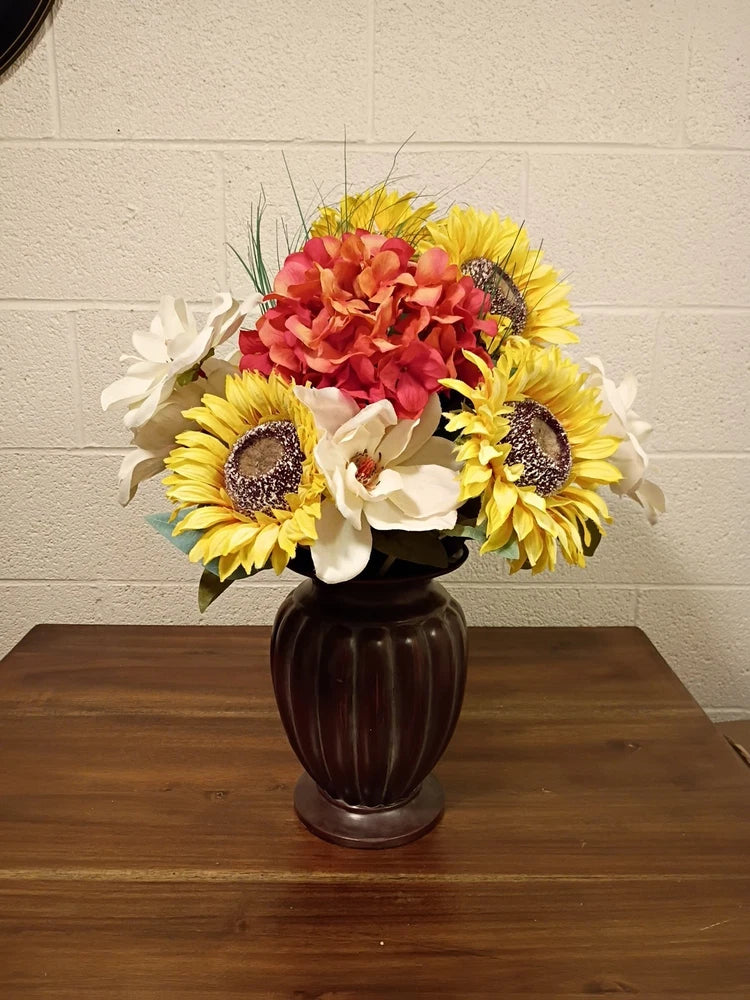 Silk flower bouquet with yellow sunflowers and red blooms in dark bronze vase