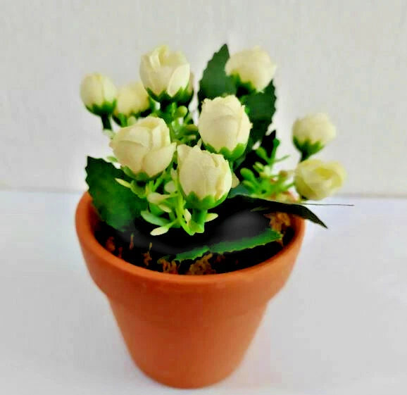 Artificial bonsai flower arrangement with pale yellow roses and green leaves in terracotta pot