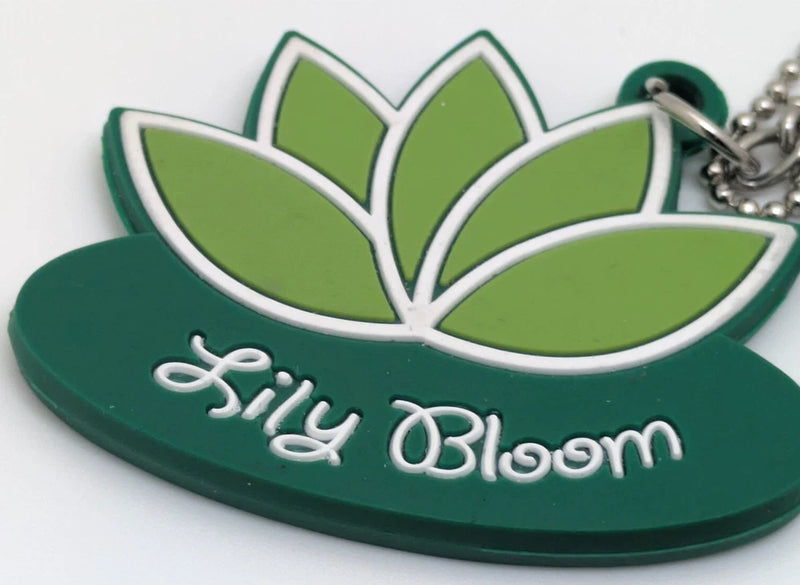 Green lily-shaped keychain with outlined flower, 'Lily Bloom' text, and metal chain ring