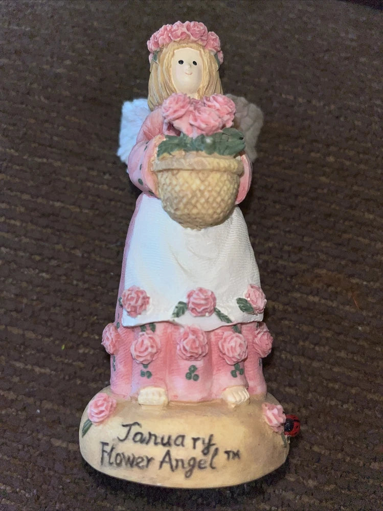 January flower angel figurine with pink bonnet and floral dress, holding basket on base.
