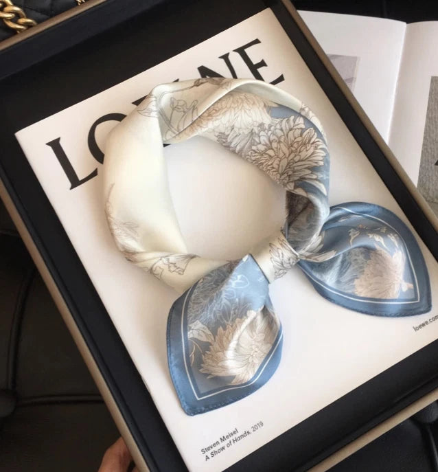 Silk bandanna scarf in white with botanical print and blue border accents, neatly folded