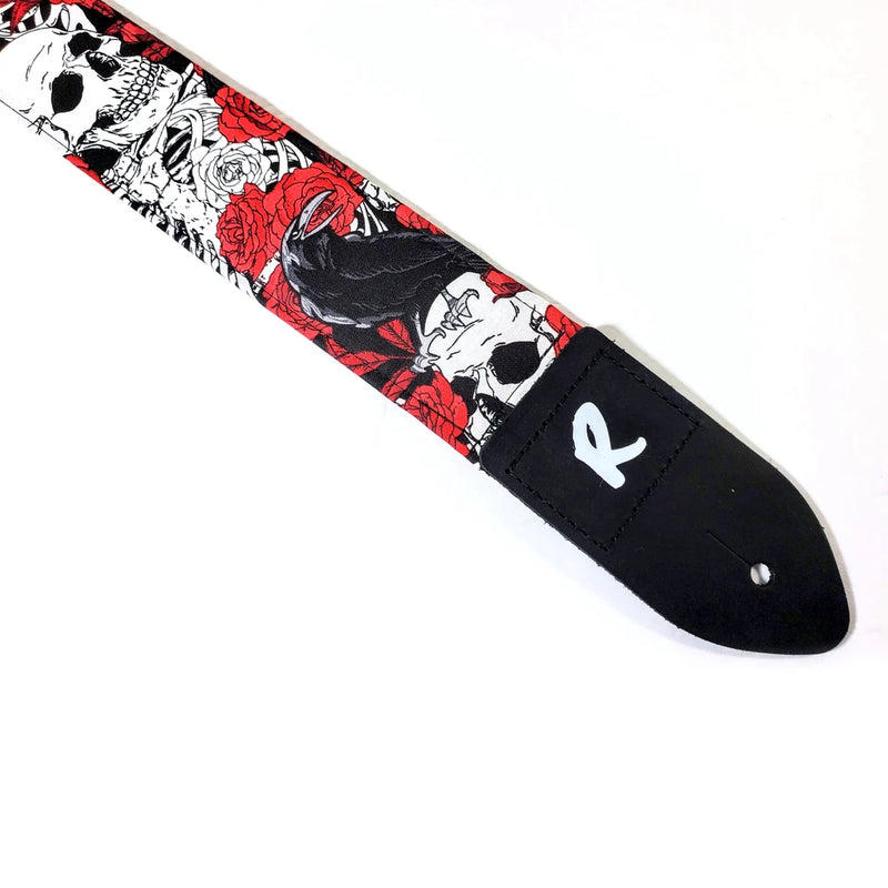 Black guitar strap with red and grey skull, rose, and raven graphic; padded end