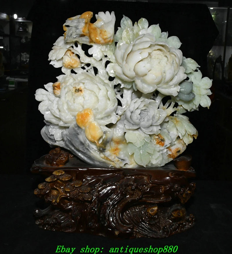 Carved jade peony and bird statue with floral details on a dark wooden base