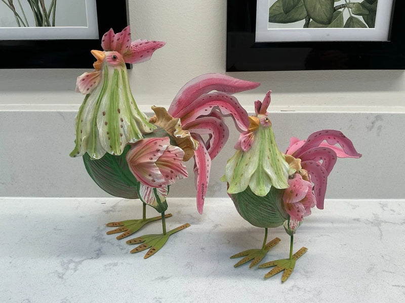 Set of two floral rooster figurines with green bodies and pink flower details, standing on feet