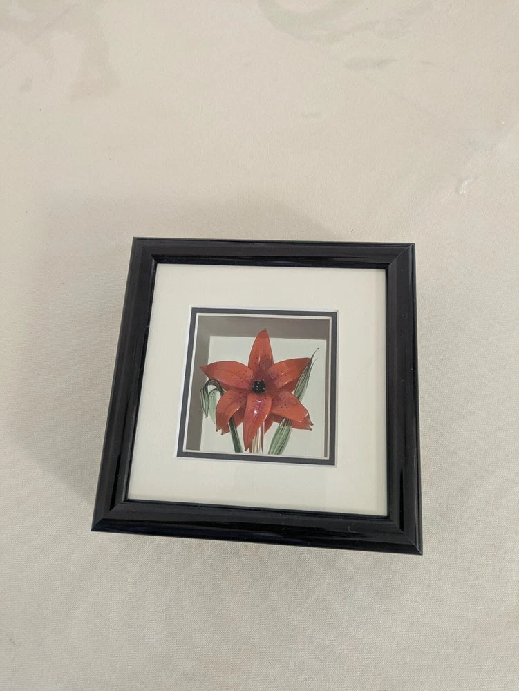 Framed red glass flower artwork with prairie lily design, dark wood-look frame