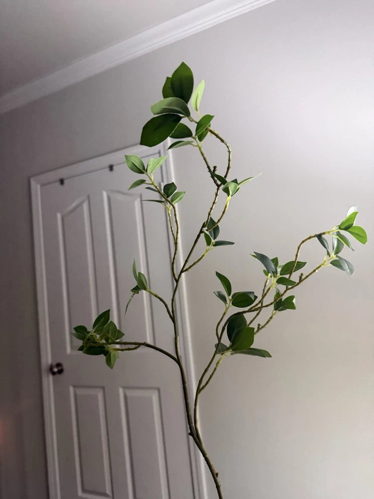 Artificial green plastic houseplant branch with small leaf sprigs, leafy decor stem