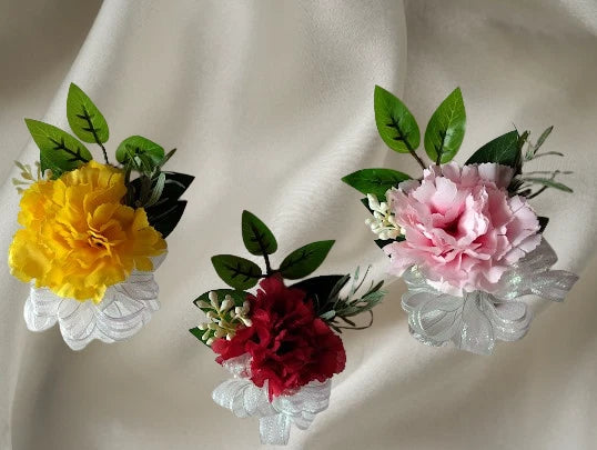 Pin-on carnation boutonniere set with yellow, burgundy, and pink blooms plus green leaves