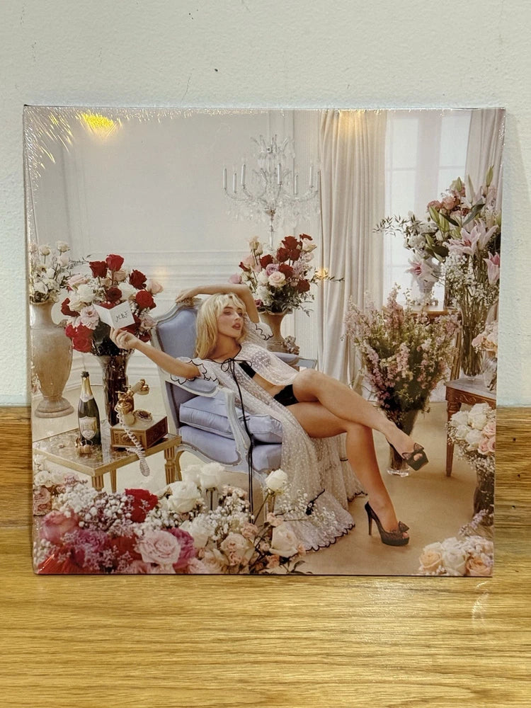 Pink champagne liquid-filled vinyl record with rose-themed artwork and seated woman